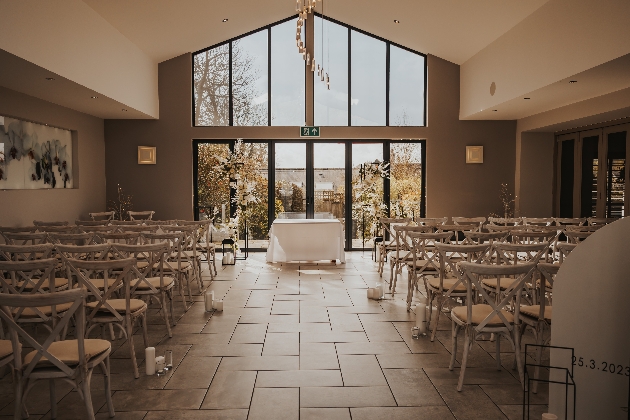 An indoor ceremony set up with glass doors at the end of the aisle