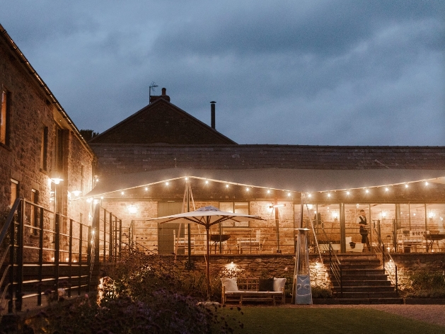 The exterior of a barn at night decorated with fairylights