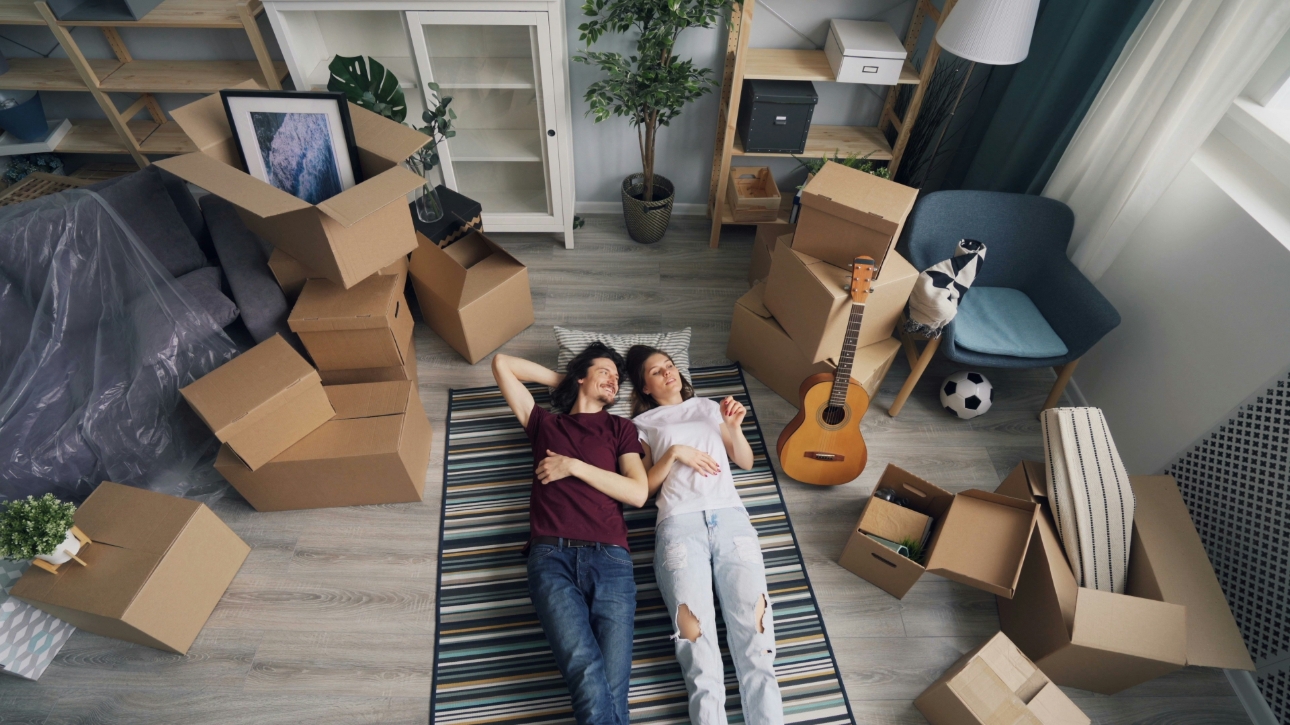 Couple laying on floor in their new home surrounded by boxes