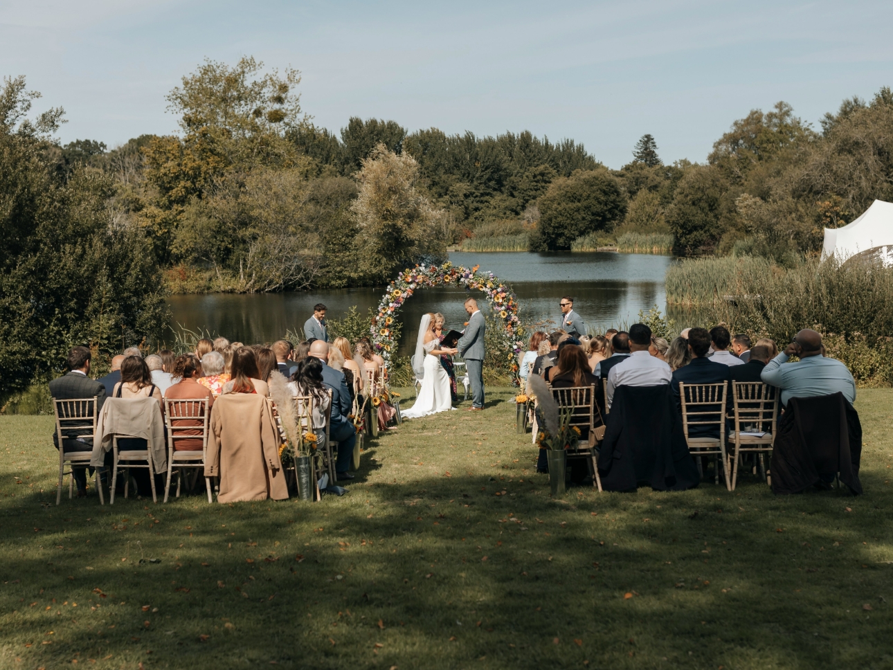 bride and groom tying the knot by a lake